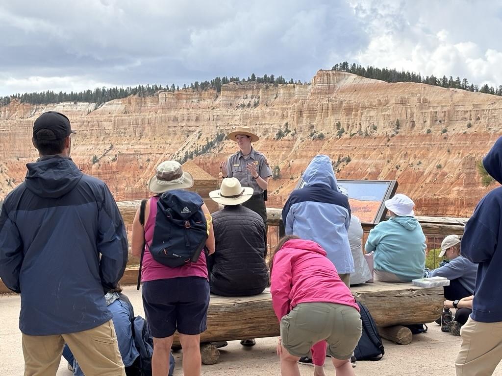 Park Ranger in uniform stands in front of multiple visitors.