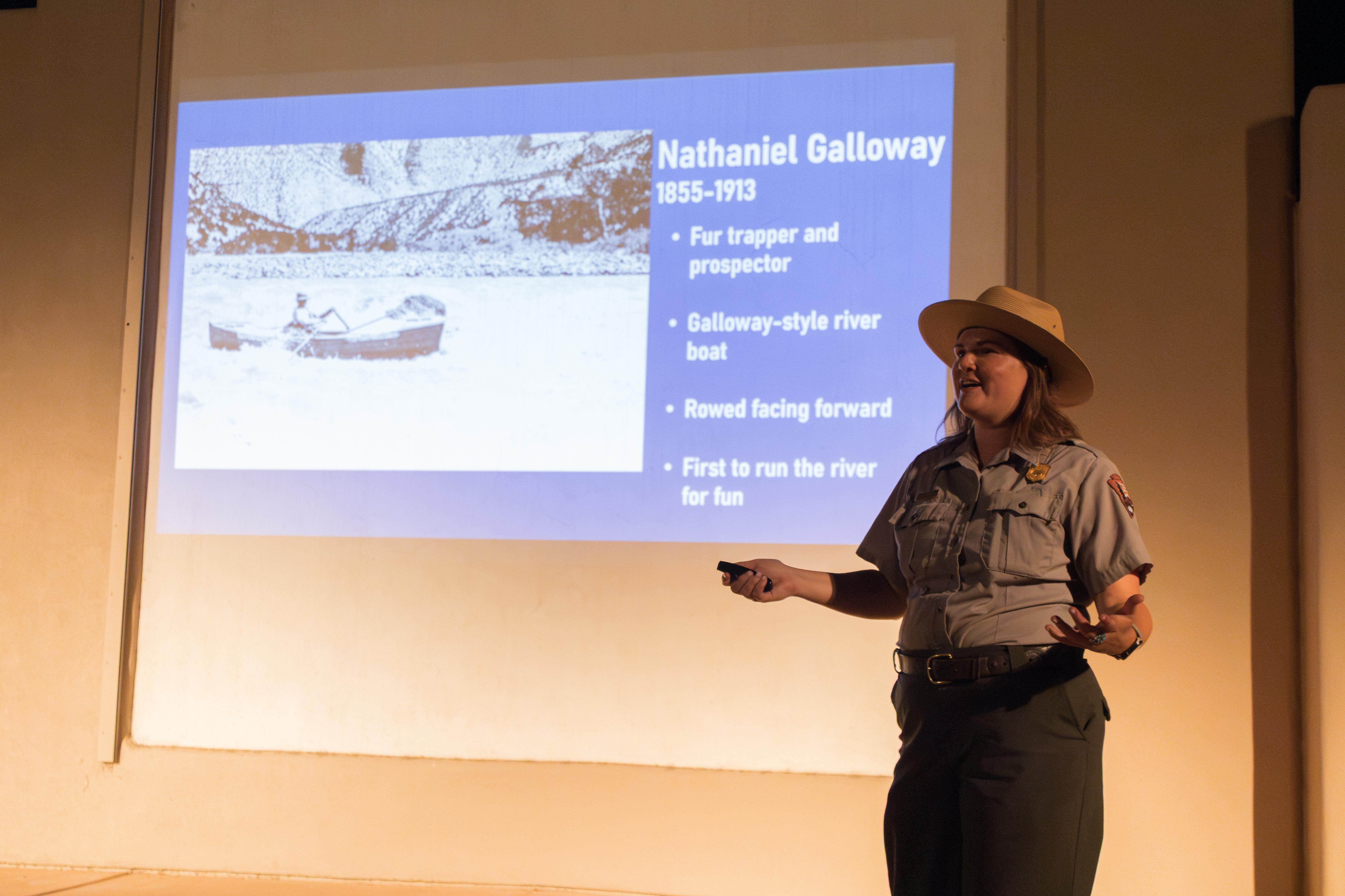 A Park Ranger stands in front of a sildeshow projection.
