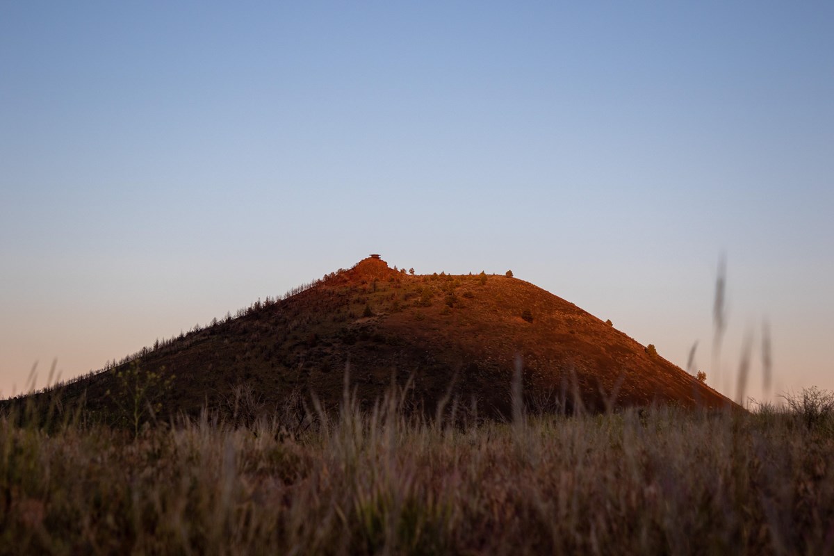 A butte in the distance with a fire tower on top at dusk