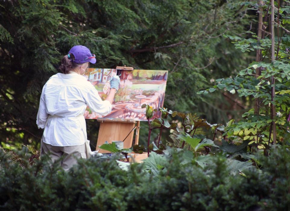 Artist in purple hat in the garden painting