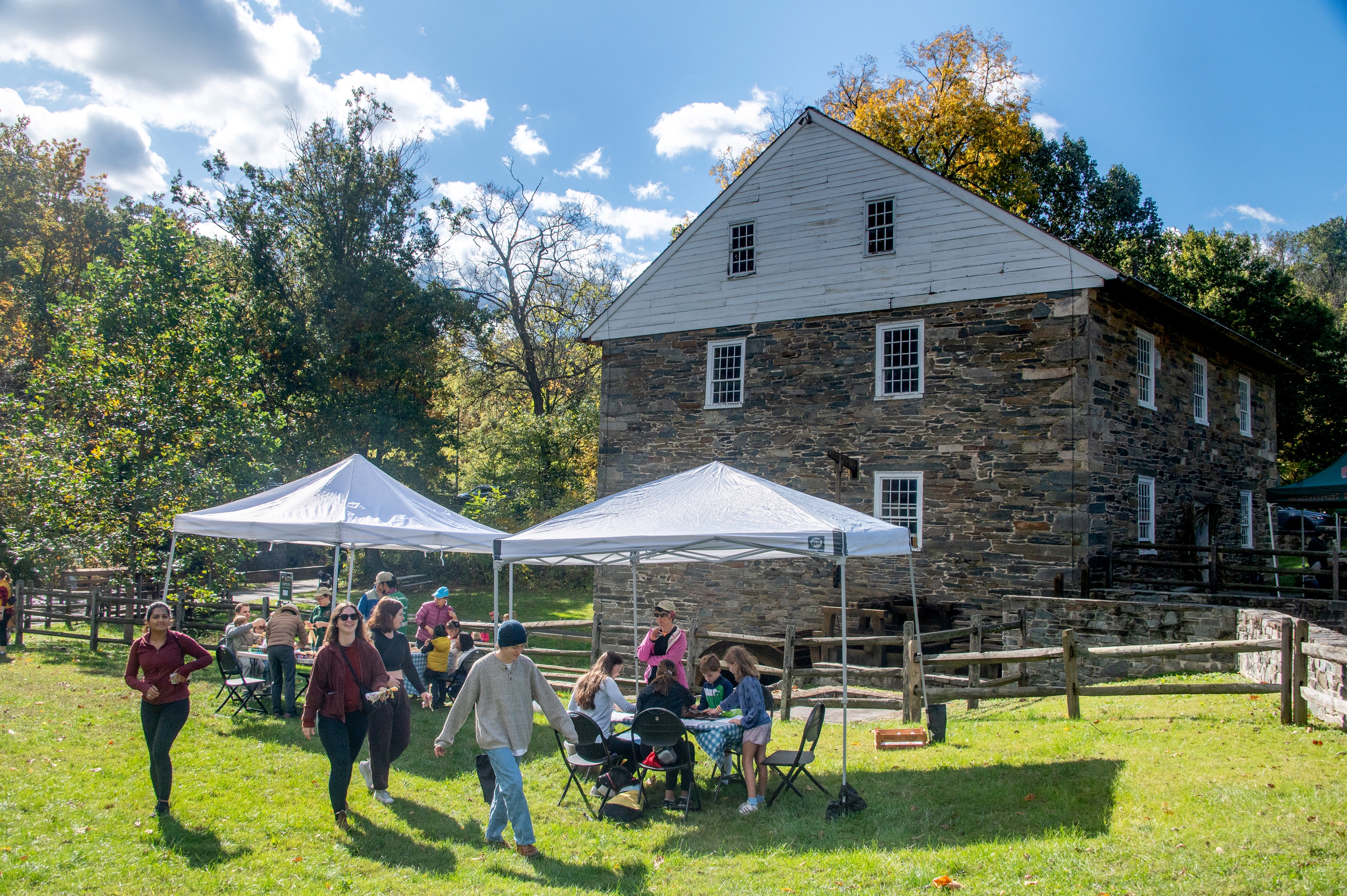 visitors gather near Peirce Mill, under pop-up tents, for activities during a special event