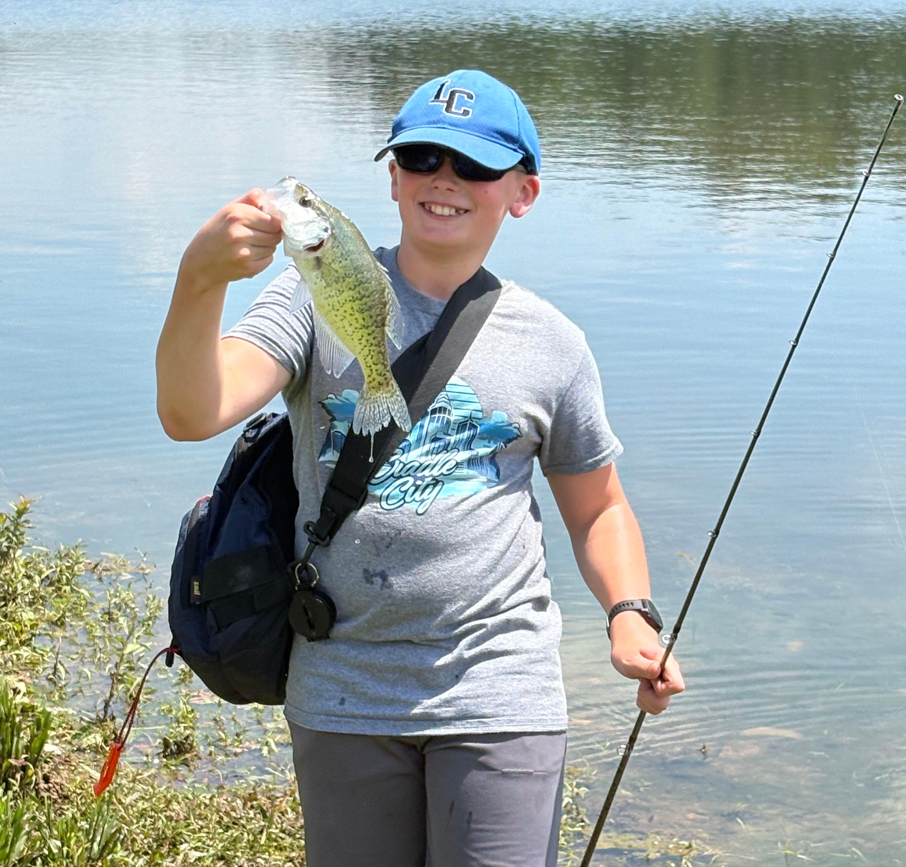 A color photo showing a young boy holding a fish