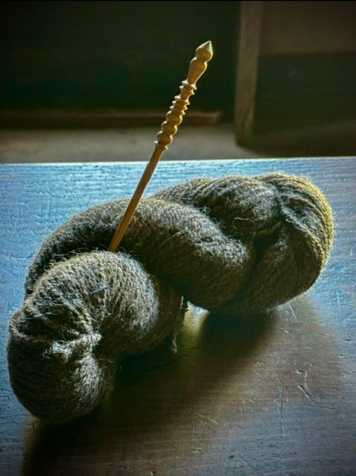 Yarn on a table with a needle in it.