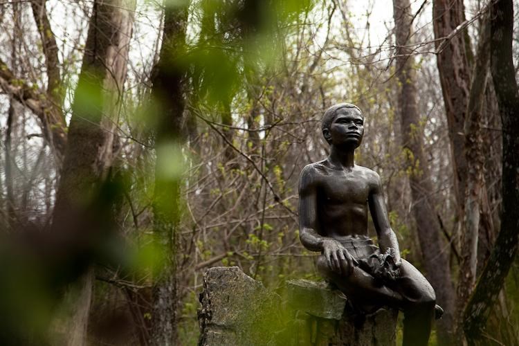 Bronze statue of young George Washington Carver holding a plant.