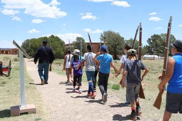 A park ranger dressed as Civil War soldier walks in front of children who carry mock muskets