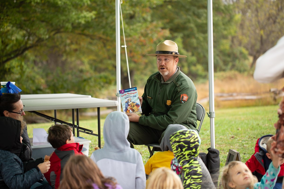 A park ranger reads a story to a group of children.