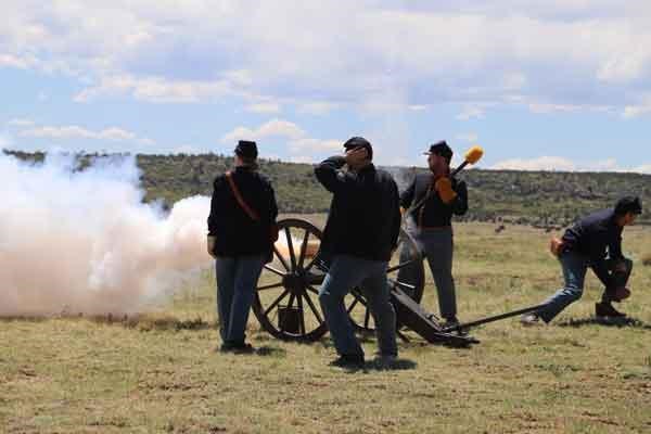 A group of park rangers dressed as Civil war soldiers fire a cannon, belching smoke