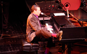 Joe Kennedy performs at piano using two hands and his right foot.
