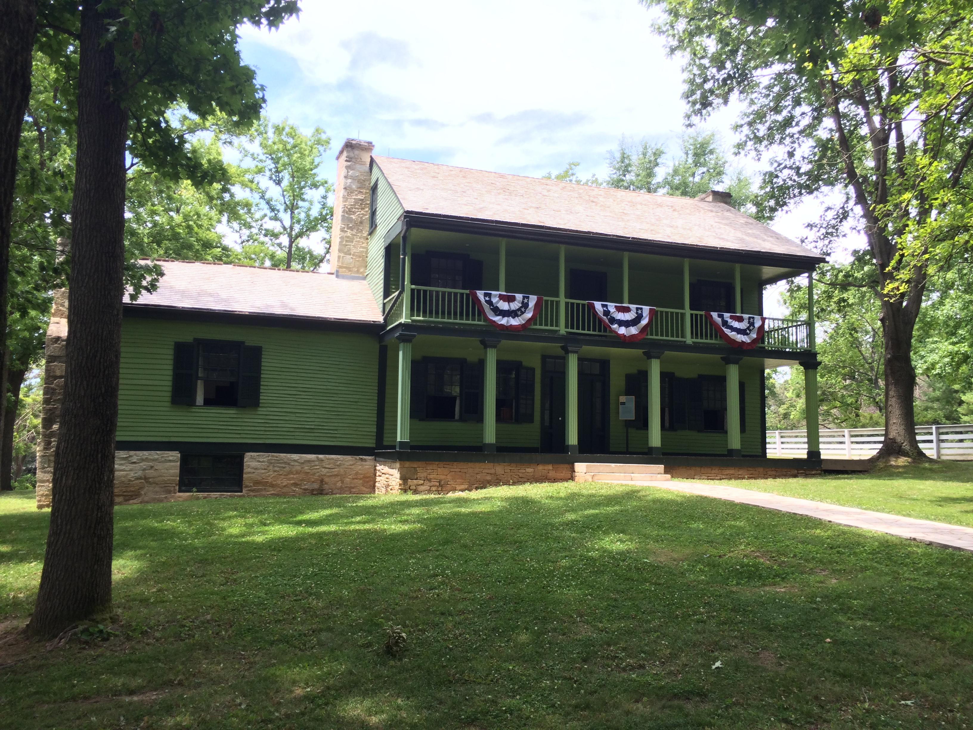 Green two-story house with red, white, and blue bunting