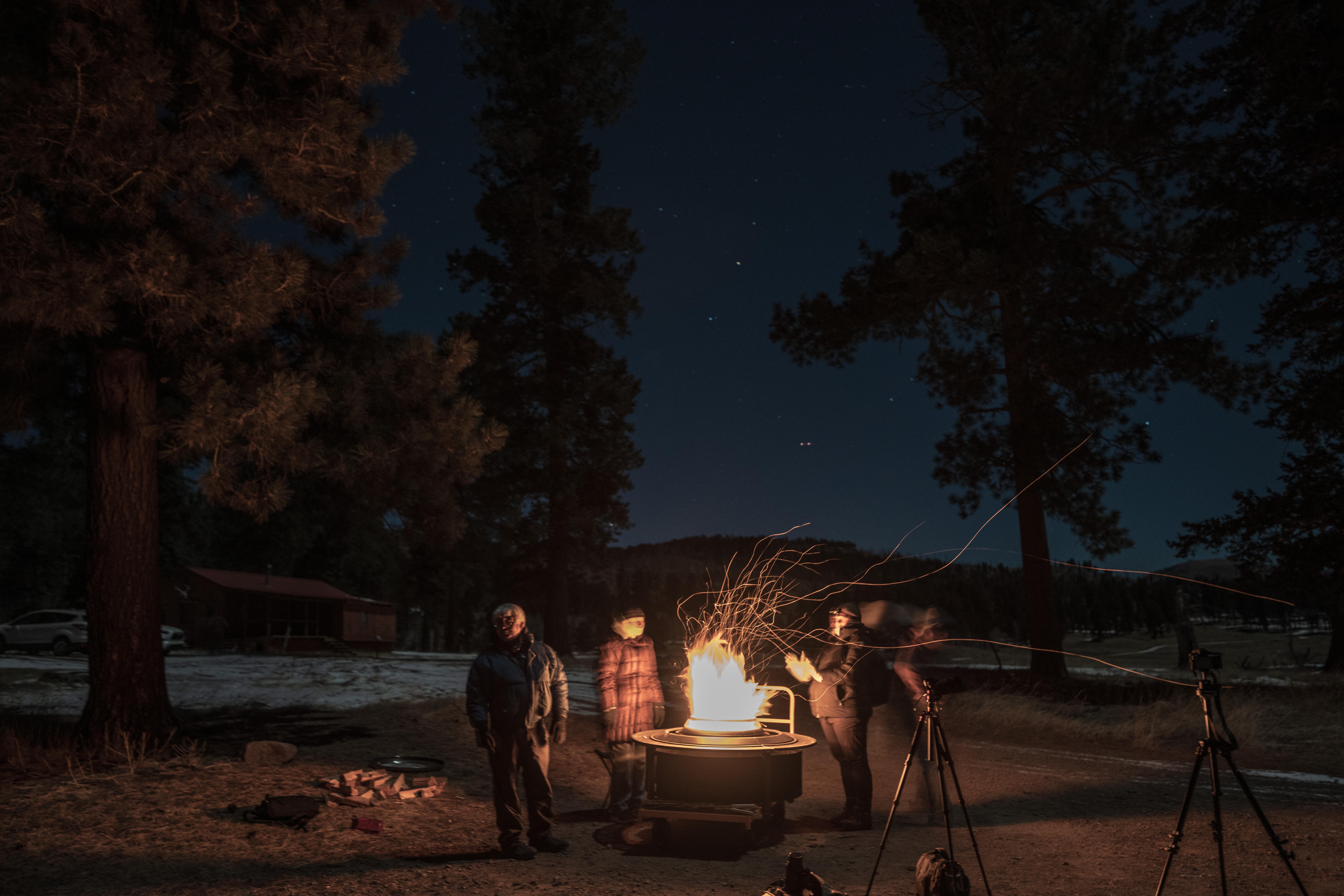 People gathered around a campfire under a starry night sky.