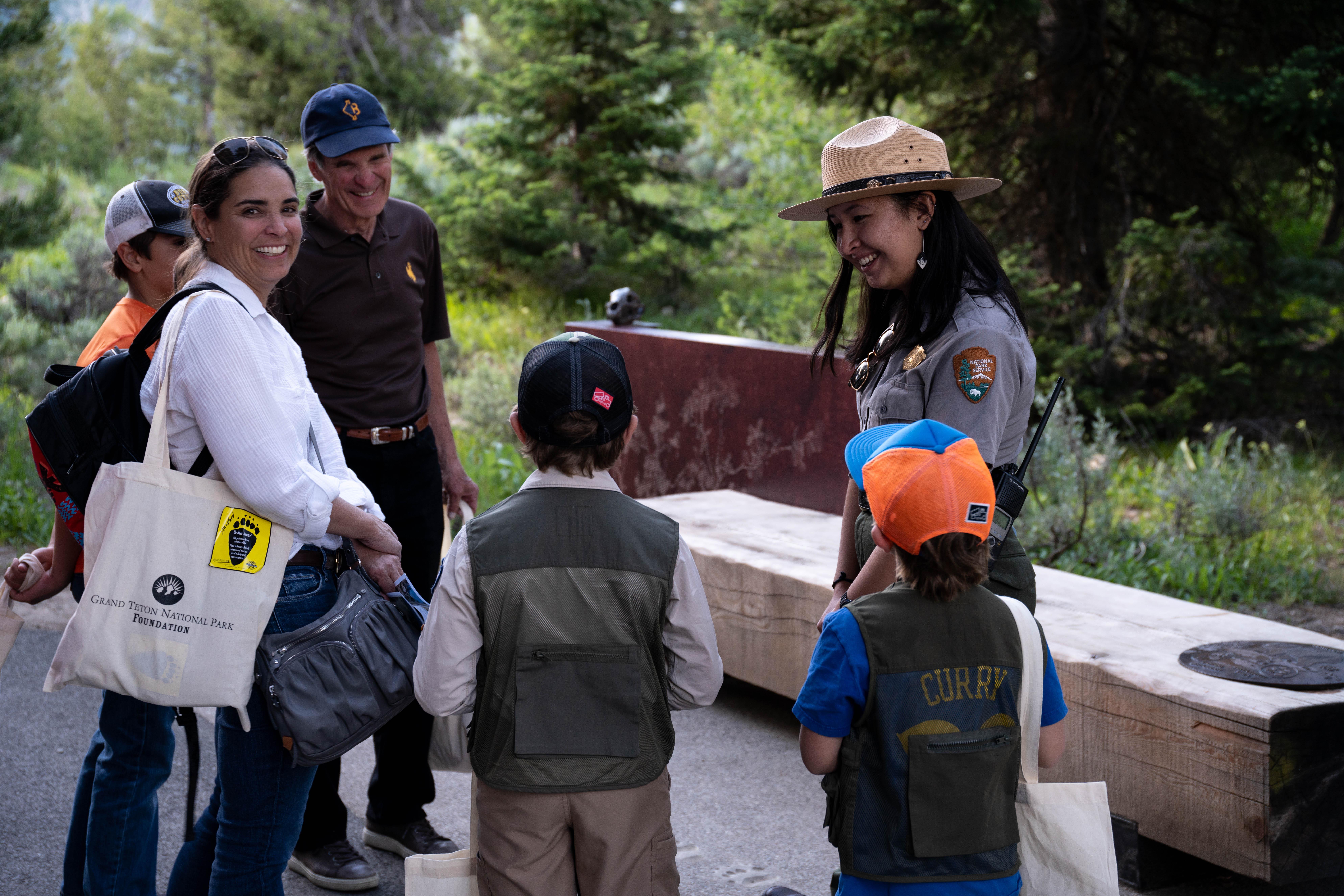 A ranger talks to a group of visitors outside surrounded by trees.