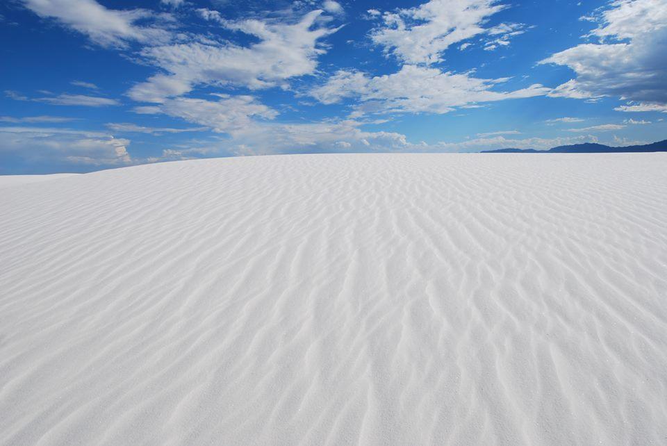 Blue sky over a white sand dune