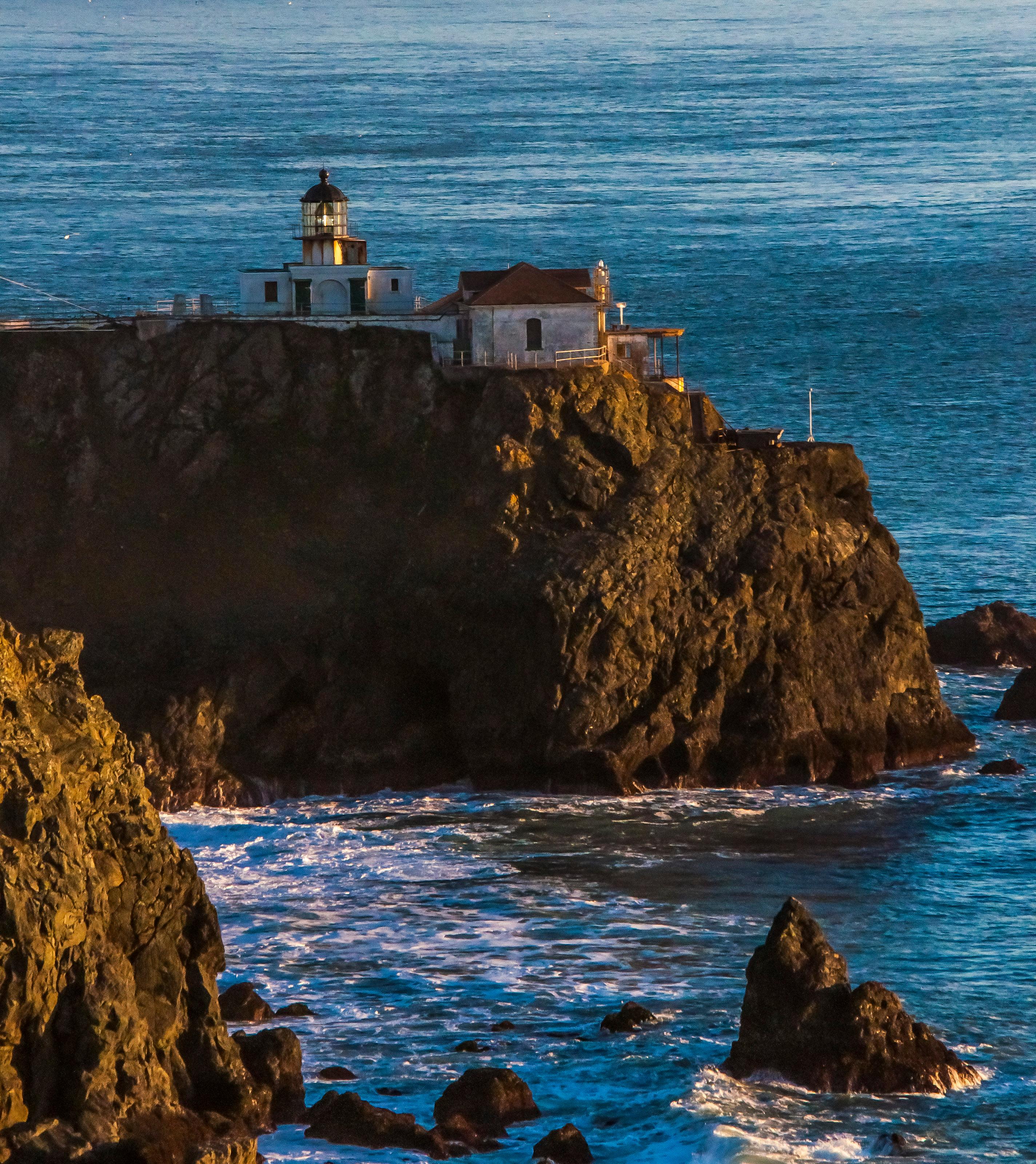 The Point Bonita Lighthouse surrounded by frothy waves and steep cliffs.