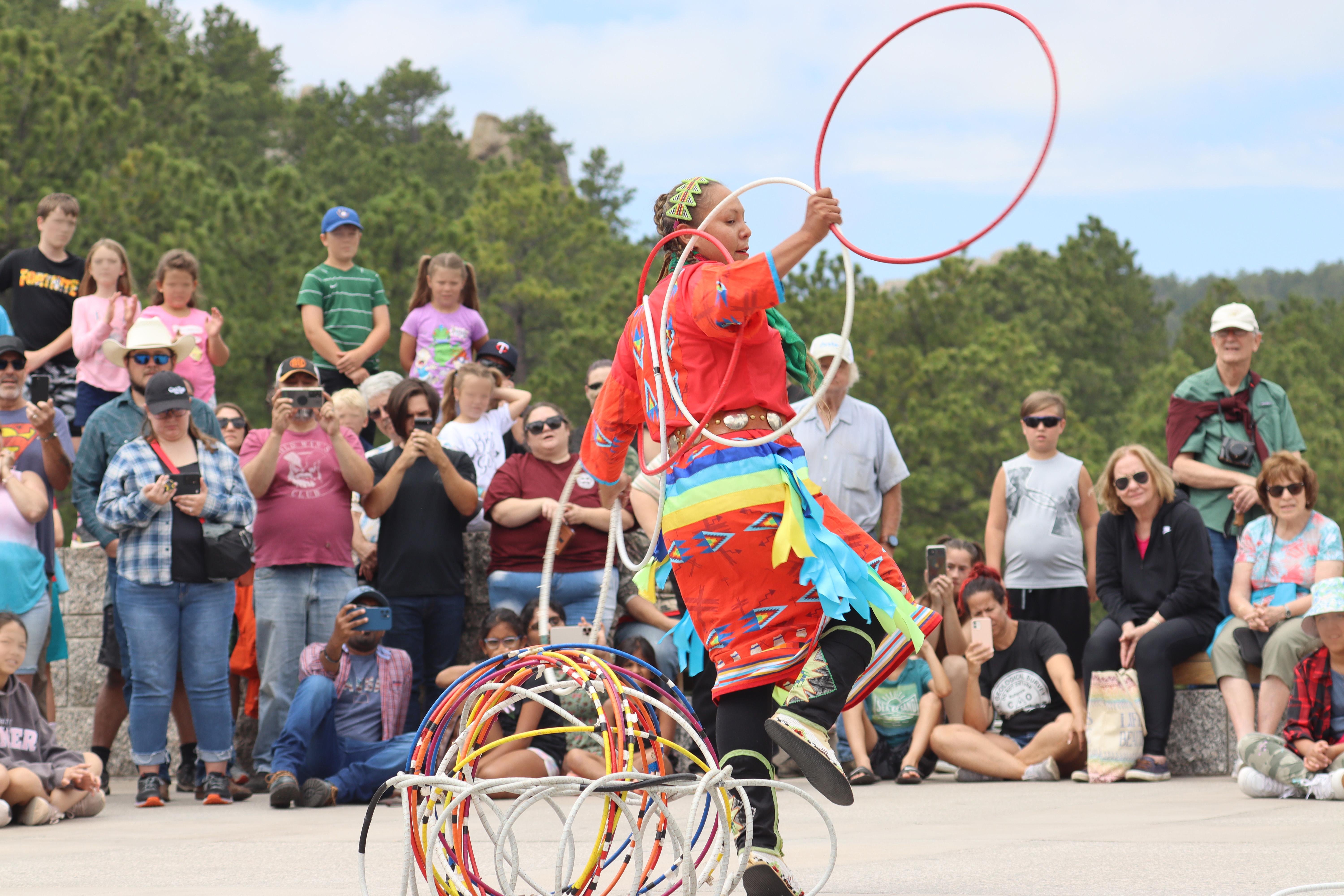 Hoop dancer performing with colorful hoops before a crowd at an outdoor event