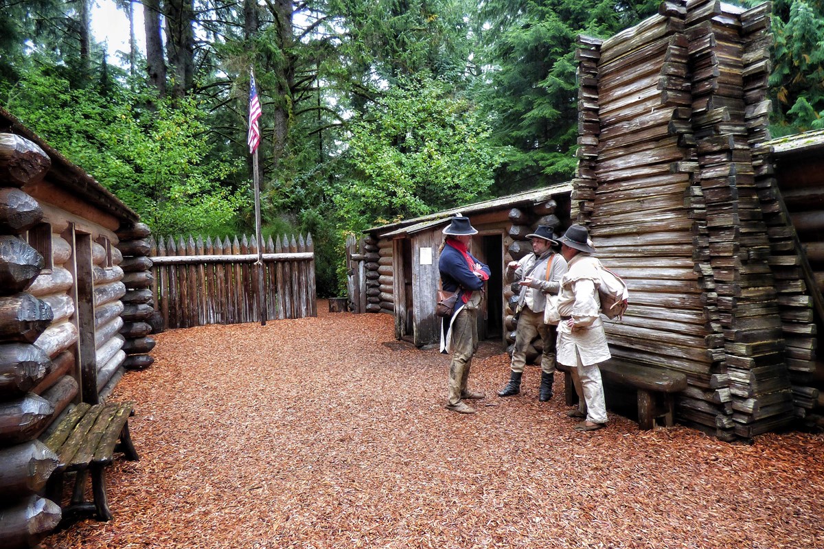 3 rangers in costume conversing inside the Fort Clatsop exhibit