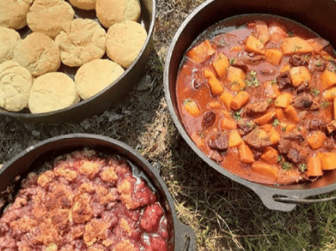 A color photograph of three cast iron pots, Dutch ovens, holding biscuits, stew and cobbler.