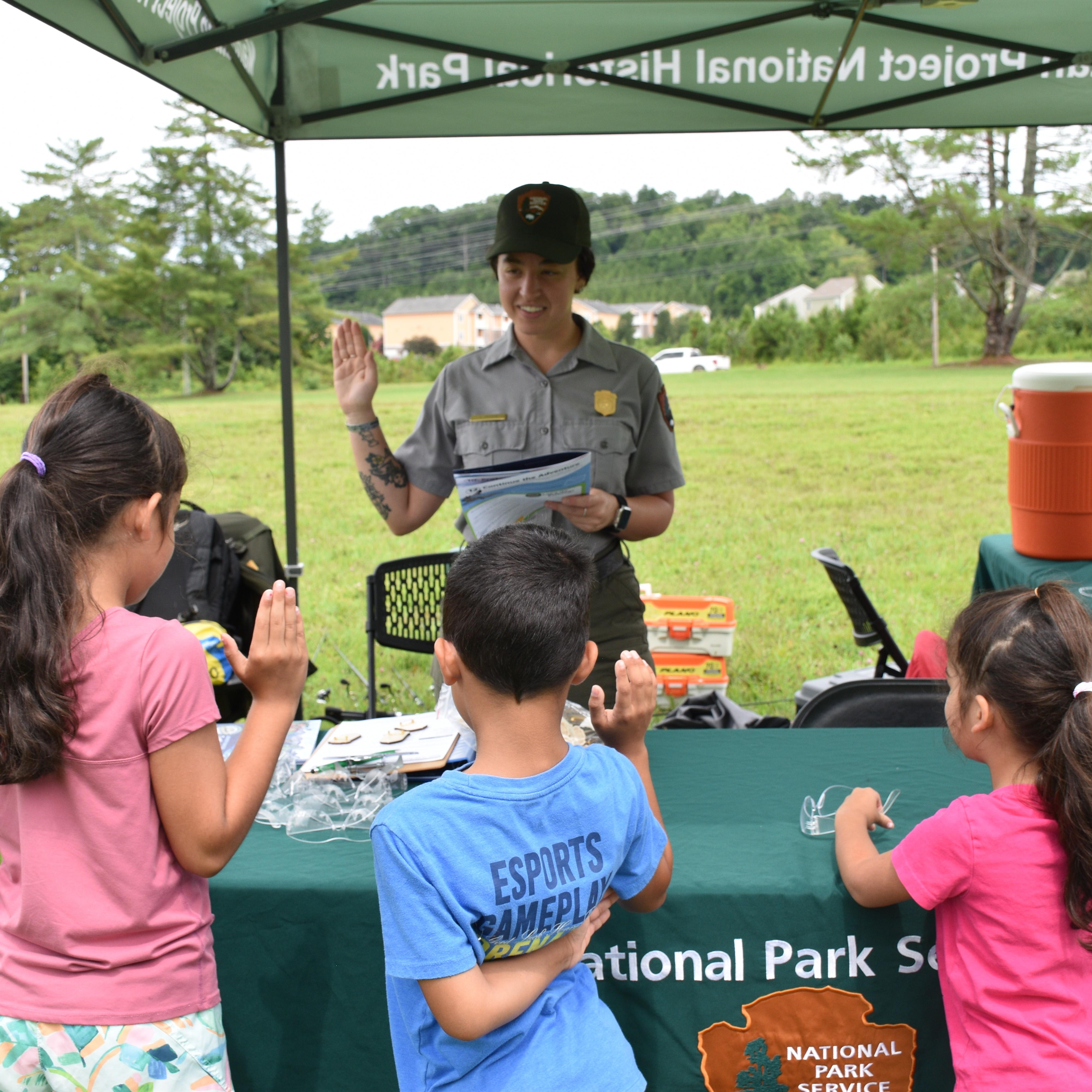 Three Junior Rangers stand facing away from the camera. They are being sworn in as Junior Rangers.