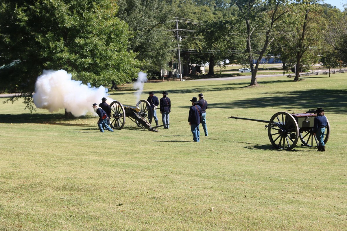 Living historians in blue uniforms fire a cannon.