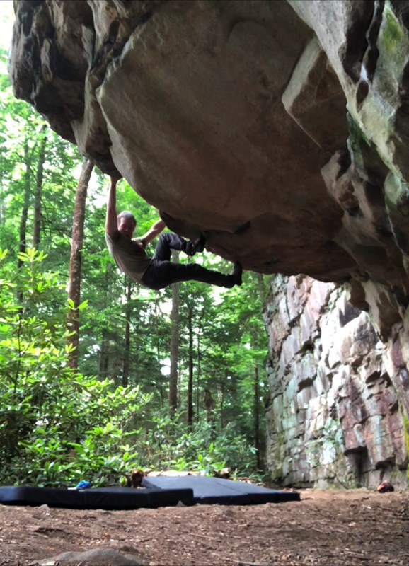 A climber on the underside of an overhanging boulder