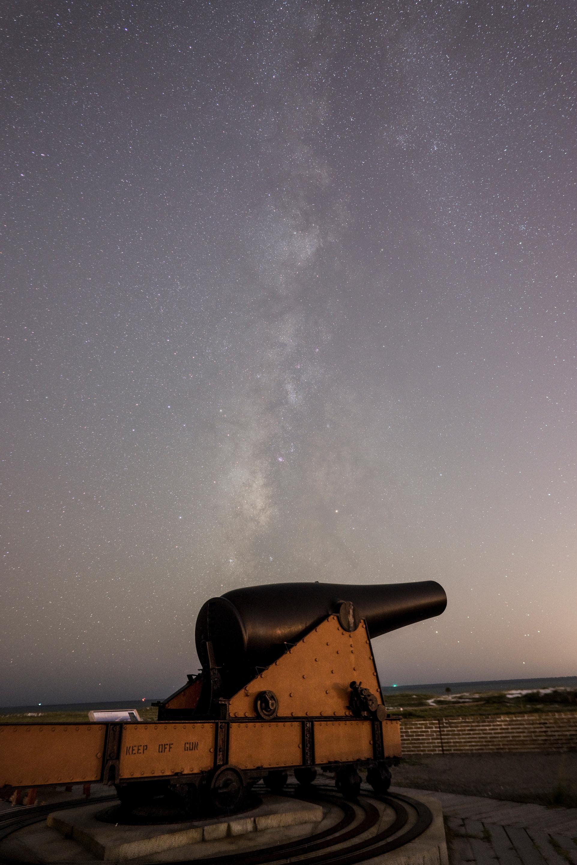 Night time photo of the milky way extending over a Civil War era cannon.