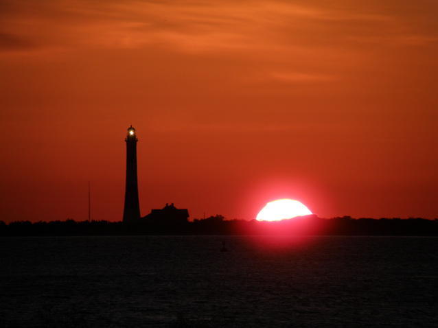 The Seashore and Fire Island Lighthouse silhouetted by the sun. The Seashore and Fire Island Lighthouse silhouetted by the sun.