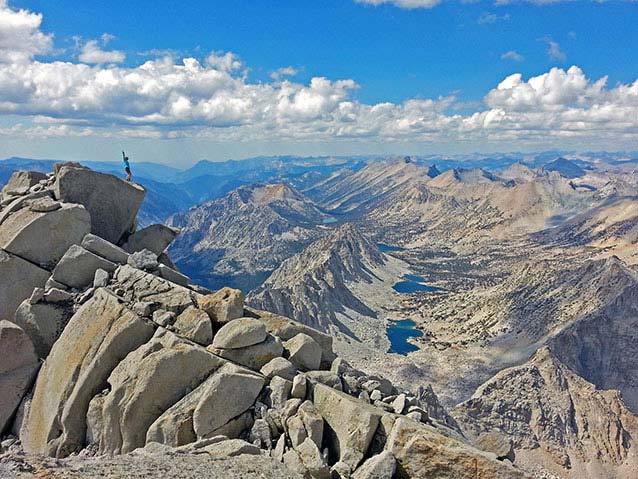 A woman stands with her arm raised looking over a vast wilderness landscape A woman stands with her arm raised looking over a vast wilderness landscape