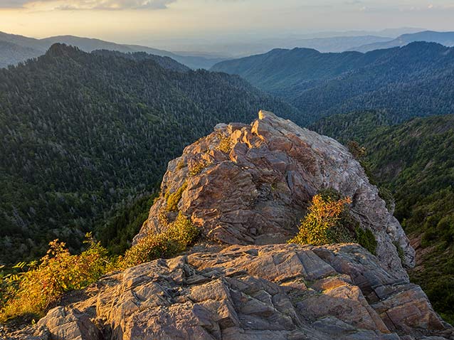 A knobby, rock outcrop overlooks mountain ridges. A knobby, rock outcrop overlooks mountain ridges.