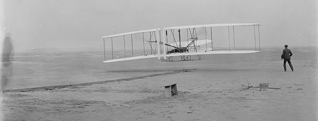The iconic first flight with Wilbur standing and Orville piloting the 1903 Wright Flyer. The iconic first flight with Wilbur standing and Orville piloting the 1903 Wright Flyer.