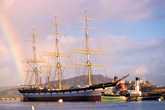 A full-rigged sailing ship with a rainbow behind it. A full-rigged sailing ship with a rainbow behind it.