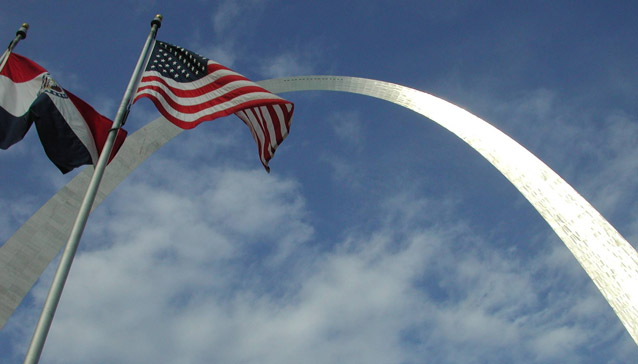 Looking up at the Gateway Arch with the Missouri state flag and the United States flag flying Looking up at the Gateway Arch with the Missouri state flag and the United States flag flying