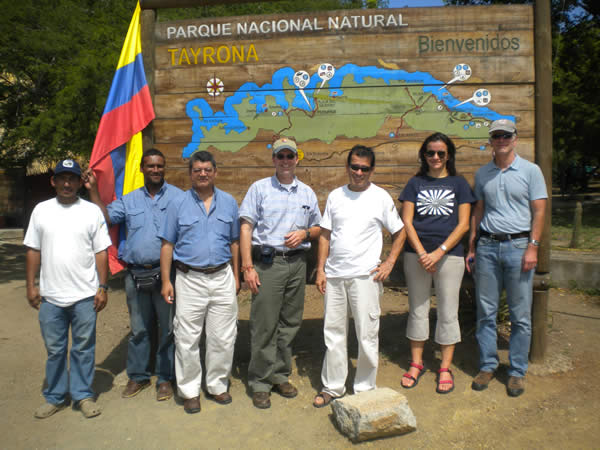 A group of friends stand in front of the Tayrona National Park sign in Colombia. A group of friends stand in front of the Tayrona National Park sign in Colombia.
