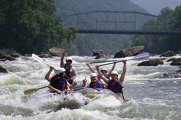 A raft coming through whitewater rapids on the Lower New River with a bridge in the background. A raft coming through whitewater rapids on the Lower New River with a bridge in the background.