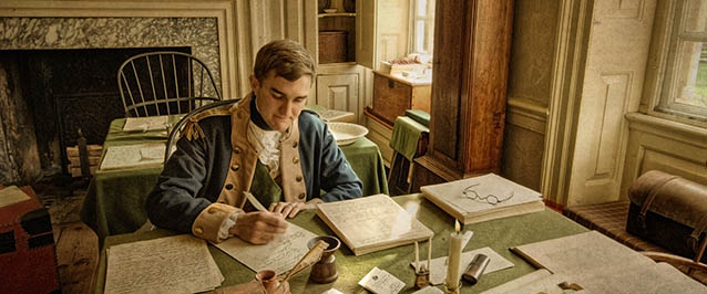 A Revolutionary War officer sitting at a desk writing letters. A Revolutionary War officer sitting at a desk writing letters.