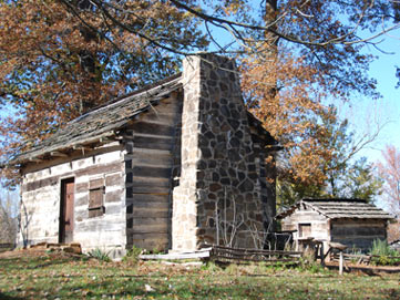 Replica Log Cabin surrounded by trees changing colors in the fall. Replica Log Cabin surrounded by trees changing colors in the fall.