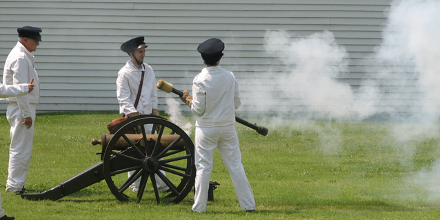 Three soldiers in white uniforms firing a cannan Three soldiers in white uniforms firing a cannan