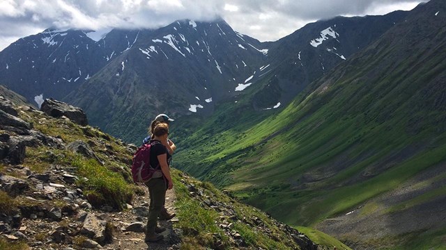 Two hikers looking out at Crow Pass Trail.