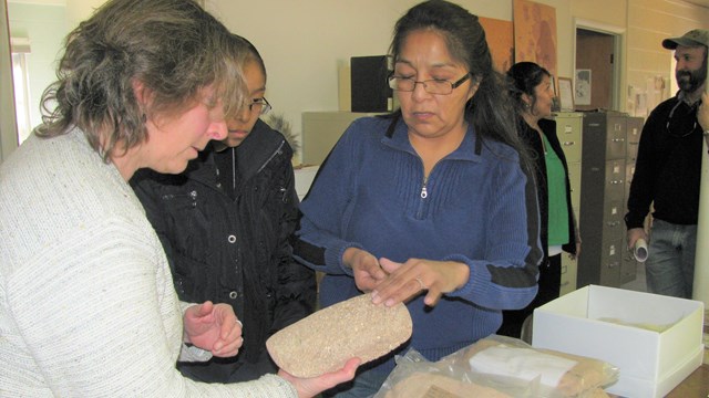 Hopi tribal member talking to a curator holding stone objects