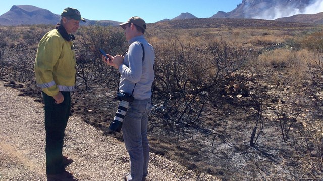 Big Bend NP employee talking to the media about a wildfire in the distance. 