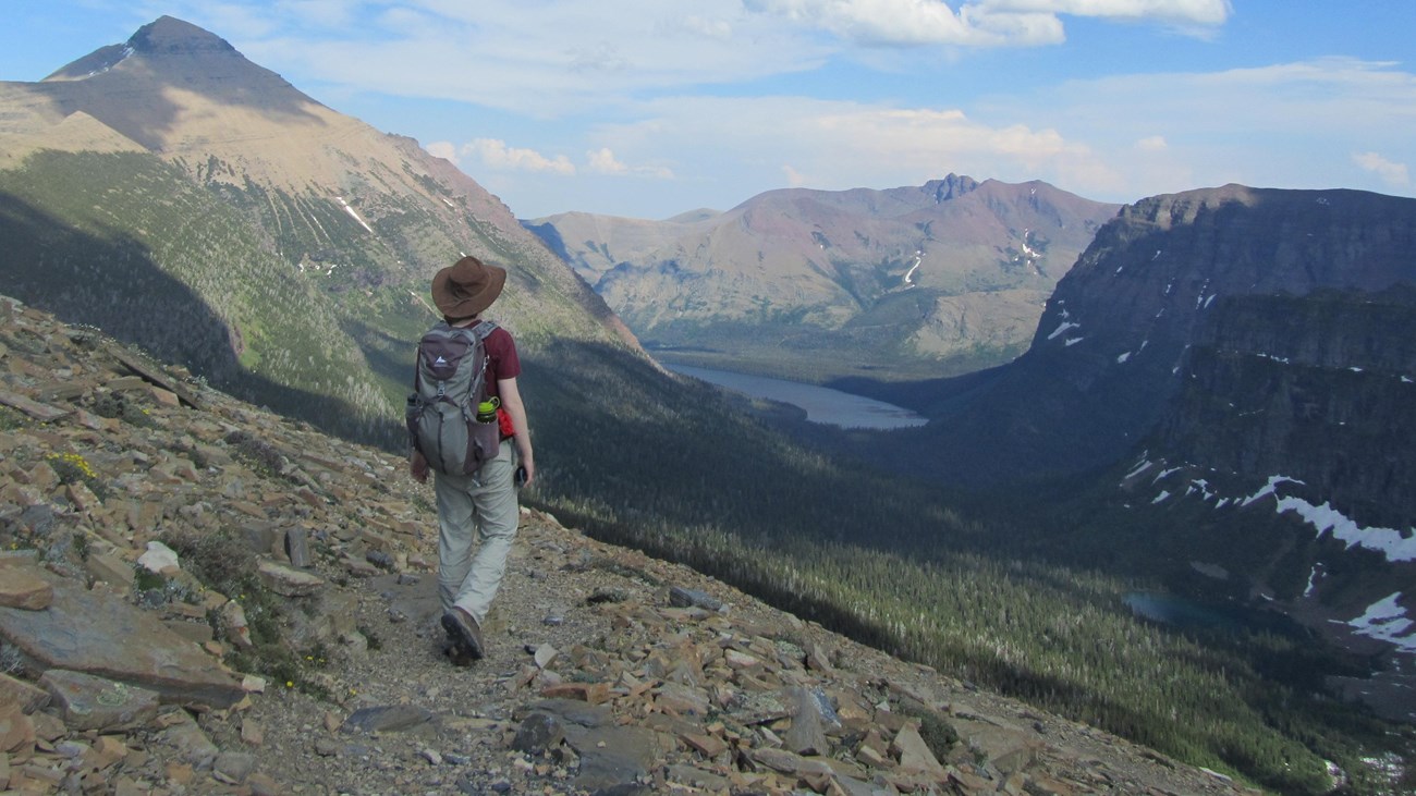 photo of two people working on layered rock with a lake and buttes in the distance