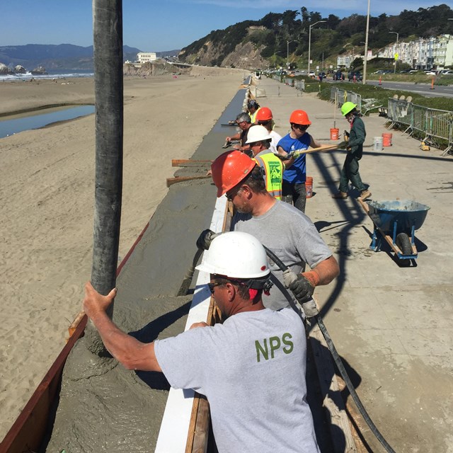 A team of NPS employees pours concrete into a wall.