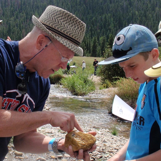 A scientist shows youths larvae living on a rock