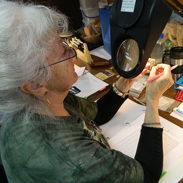 Woman looking at an artifact through a magnifying glass