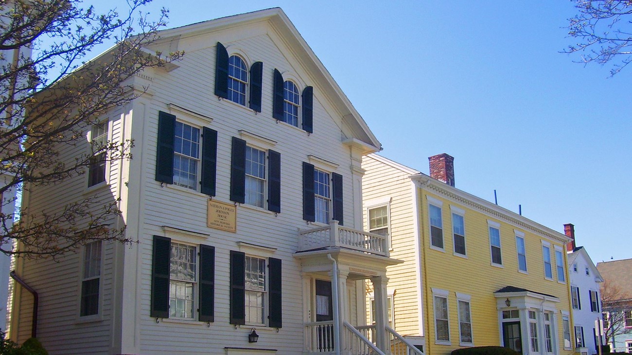 Two house fronts side by side, one white, one yellow.