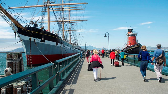 people walking along a city pier in san francisco harbor