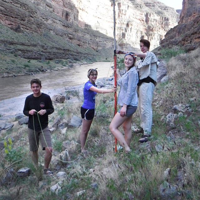 group of 4 students using equipment near a river