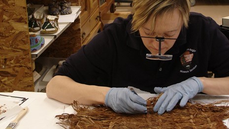 A woman inspects woven plant fibers.