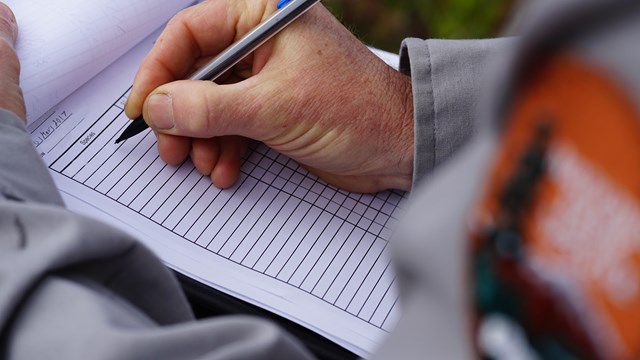 A researcher recording observations on a clipboard