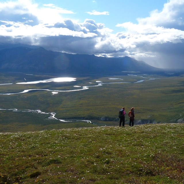 People in a large open area surrounded by mountains.