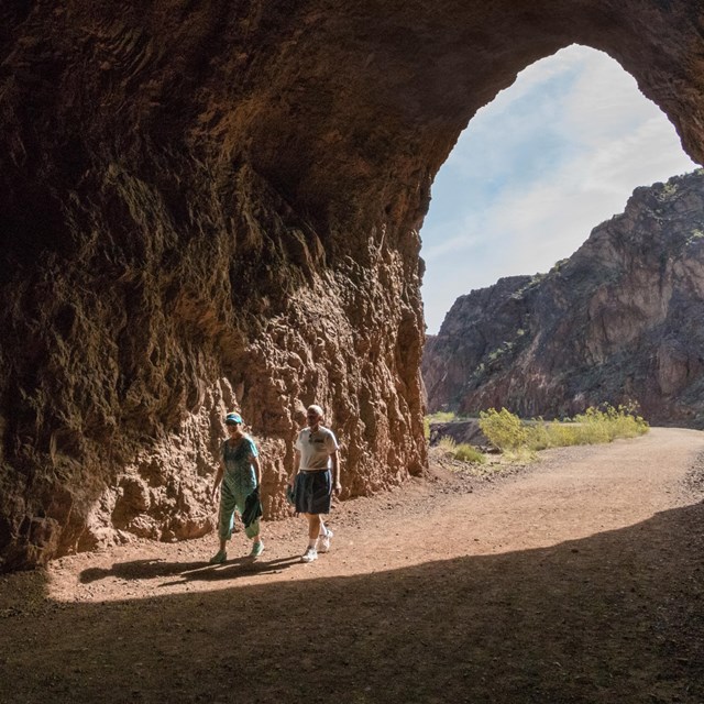 Two people walking through an abandoned trail tunnel in the desert