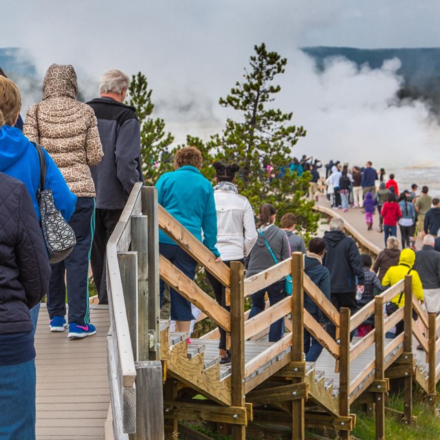 visitors waiting in a long line on the boardwalk of a Yellowstone geyser